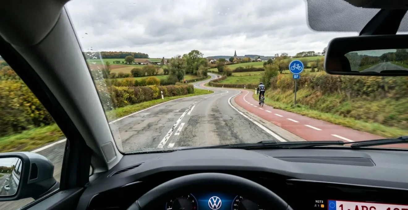 Route de campagne sinueuse belge avec marquages effacés et piste cyclable adjacente, perspective depuis l'habitacle