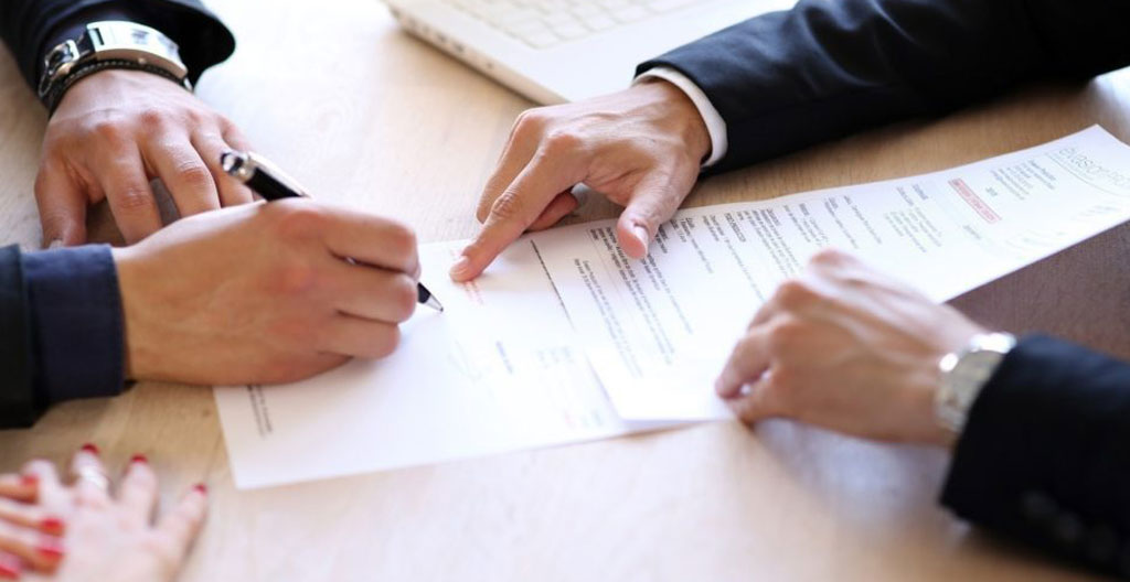 Gros plan sur des mains tenant un contrat et des clés de voiture posés sur un bureau avec des documents administratifs